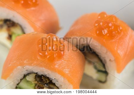 Sushi Rolls With Salmon, Avocado And Cream Cheese, Decorated With Red Caviar, Served On White Slate.