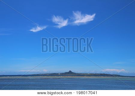 Clear blue sky with bird-like clouds and skyline of the mountain