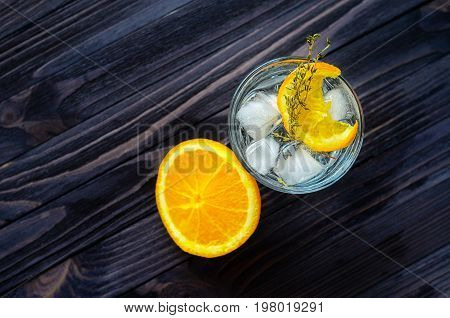 Cut orange near the alcoholic cocktail on dark wood table top view. Blank space for text placement