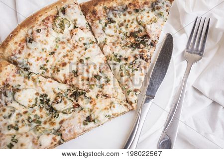 Three pieces of pizza on a white plate a silver knife and fork