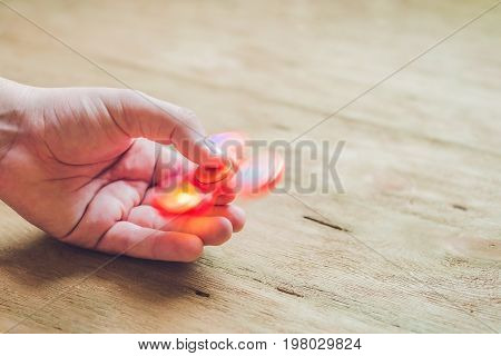 A Man Hand Holding Hand Spinner Or Fidget Spinner Over Wooden Background
