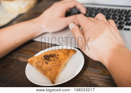 Appetizing samsa on a white plate next to the laptop