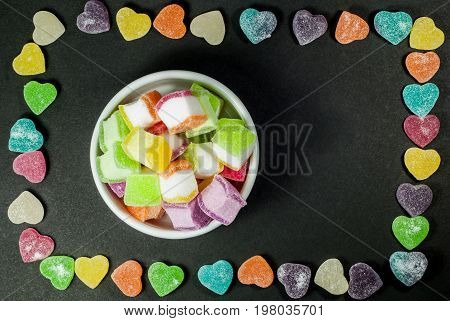 Multicolored jelly in a white cup against a black background.
