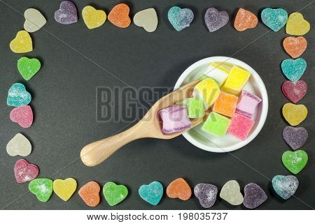 Multicolored jelly in a white cup against a black background.