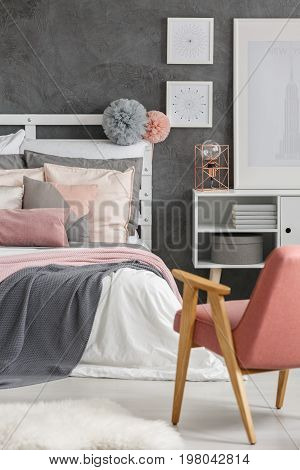 Two fluffy pompoms hanging on wooden bedheads in room with posters