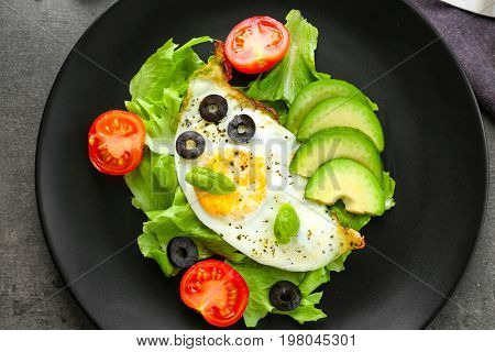 Plate with over hard fried egg and vegetables on dark table