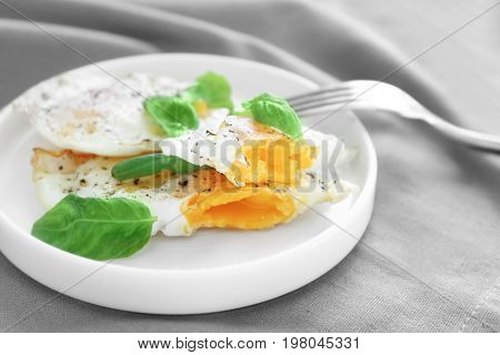 Plate with delicious over hard fried eggs on tablecloth