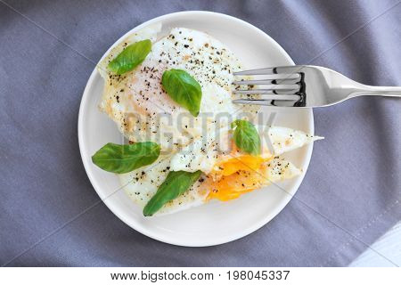 Plate with delicious over hard fried eggs on tablecloth
