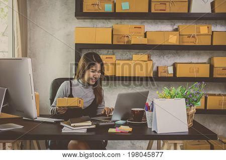 Young asian teenager owner business woman work at home for online shopping checking order and prepaing package the product with office equipment entrepreneur and alpha generation life style concept