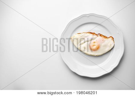 Plate with over hard fried egg on light background