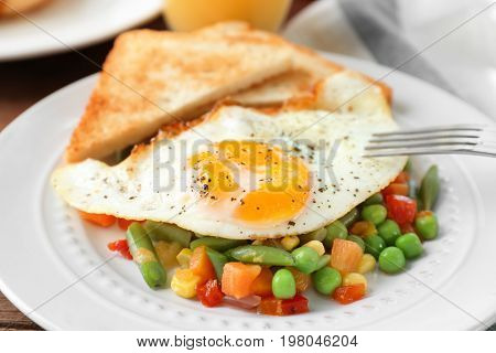 Plate with delicious over hard fried egg, toasts and vegetables, closeup