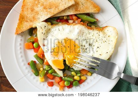 Plate with delicious over hard fried egg, toasts and vegetables, closeup