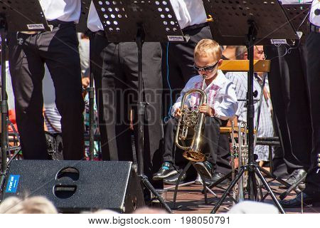 Buchlovice Czech Republic July 29 2017: Little boy plays trumpet at folk festivities. Gifted child. Traditional farmers harvest celebrations of garlic