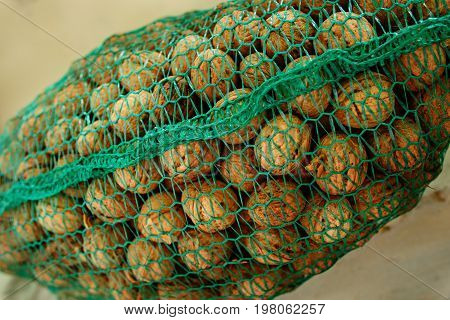 Background Of Bunch Of Unpeeled Riped Walnuts, Collected Into Green Wicker Net Bag