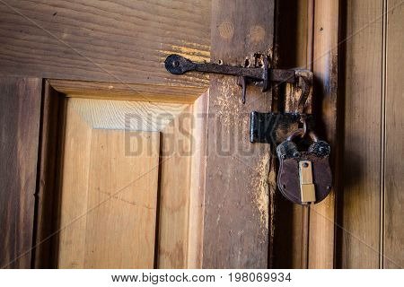 Antique Padlock On Door. An antique 18th century style brass and copper padlock on an old wooden door.