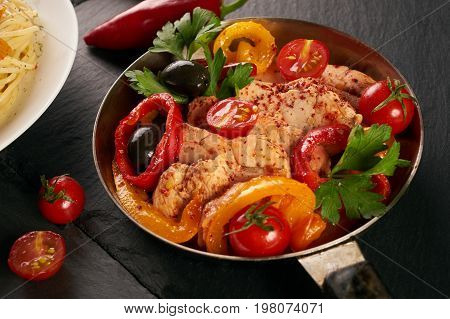 Fried chicken with vegetables on the pan and Italian pasta with a parmesan cheese basil olives paprica and tomatoes on a plate. Healthy food copncept. Top view copy space.