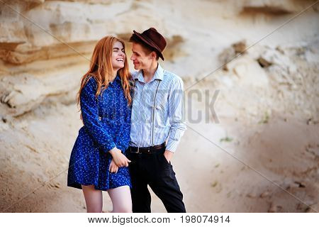 An Attractive Man Hugs A Beautiful Woman In A Blue Dress In The Middle Of A Sandy Canyon. Lovers Are