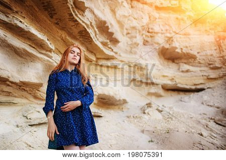 Beautiful Redheaded Girl Standing In A Blue Dress In The Middle Of A Sand Quarry