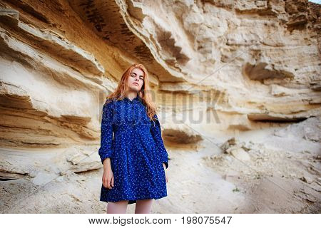 Beautiful Redheaded Girl Standing In A Blue Dress In The Middle Of A Sand Quarry