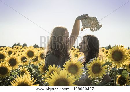Happy spontaneous attractive young couple share a good joke laughing uproariously and hugging each other outdoors in an sunflower field
