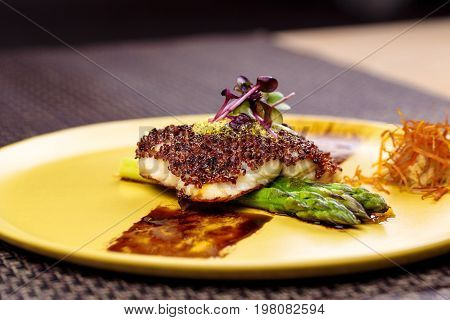 Quinoa crusted fish on asparagus on yellow plate on Wicker place mat