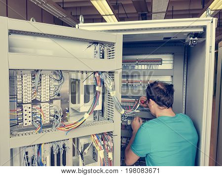 Electrical engineer configuring wires. Electrician repairing substation cubicle.