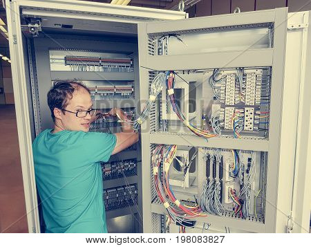 Electrical engineer configuring wires. Electrician repairing substation cubicle.