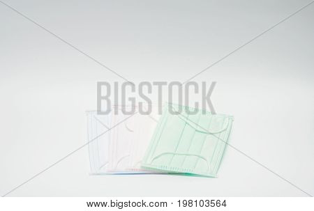 Green pink light blue and white ear loop disposable face mask overlapping used for covering mouth and nose. It protects against body fluid and large particles in the air