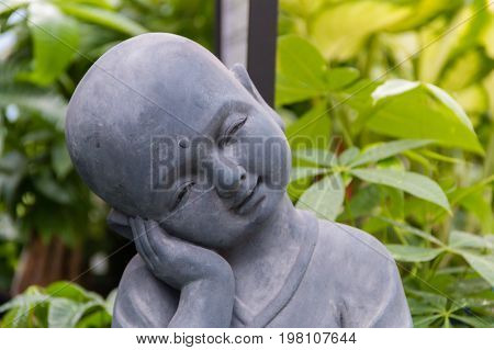 A baby buddha statue sitting in a garden.