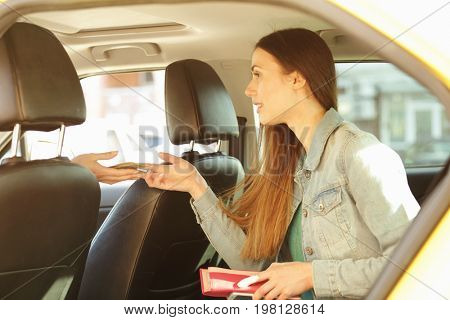 Young beautiful woman sitting on backseat and paying for taxi