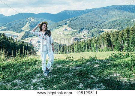 young pretty woman in hat walking by mountain peak