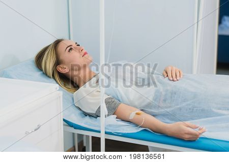 Pensive woman transfused lying in hospital ward.