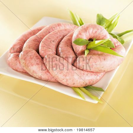 White raw sausage on a plate and yellow glossy background