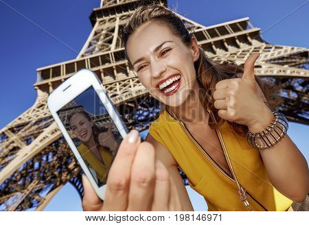 Woman Taking Selfie With Phone In Front Of Eiffel Tower In Paris