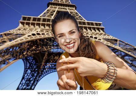 Smiling Woman Showing Hashtag Gesture Against Eiffel Tower