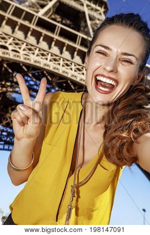 Woman Taking Selfie And Showing Victory Against Eiffel Tower