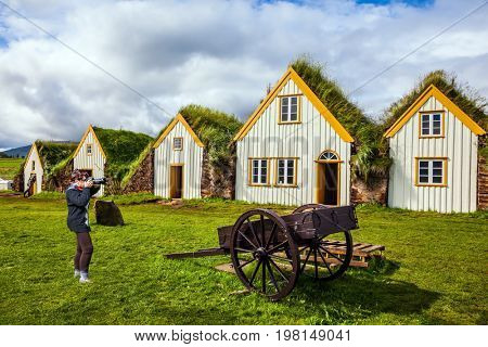 Ethnographic Museum-estate Glaumbaer, Iceland. The woman photographed the old village. The concept of the historical and cultural tourism