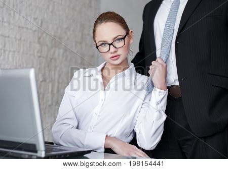 Sexy smart secretary pulling boss by tie in office seduction