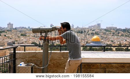 Jerusalem, Israel - May 25, 2017: Tourist looks in binoculars tower viewer at the Jerusalem Old City view. Mount of Olives is a famous Holy Land place and it has a fantastic view to the Old Jerusalem