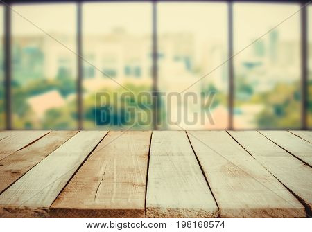 ooden table in front of abstract Blur white green background from office window