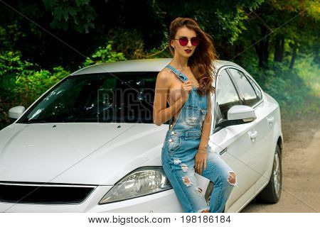 young gorgeous women in glasses sexy sits on a white car