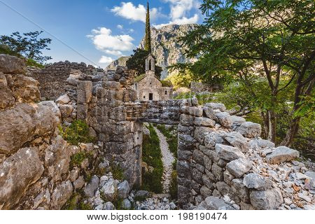 Ancient Serbian church, city ruins and mountain valley landscape near Kotor castle in Montenegro. Old mountain church and monastery in Kotor region near path to Lovchen mountain. Saint Ivan chapel.