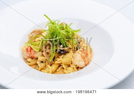 Ballerine pasta with shrimps in white plate on white tablecloth.