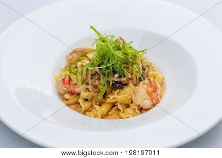 Ballerine pasta with shrimps in white plate on white tablecloth.