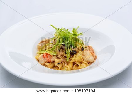 Ballerine pasta with shrimps in white plate on white tablecloth.