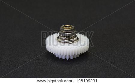 Plastic gear spare part in the fragment of machine on black background.