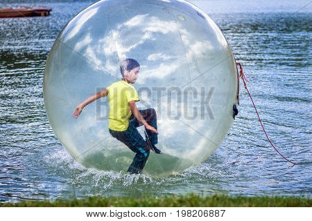 Aquazorbing. Aqua zorbing on water. Playing boy