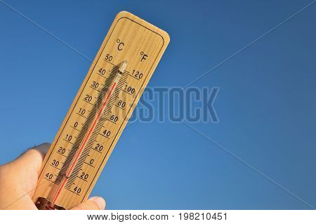 Mercury wooden thermometer shows very high temperature. Temperatures in Celsius and Fahrenheit degrees. Hot summer weather. Forty degrees over zero during the day.