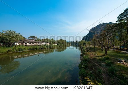 Wide angle picture of the Nam Song River with tropical vegetation and a closed resort. Near to Tham Chang Cave in the city of Vang Vieng Laos.
