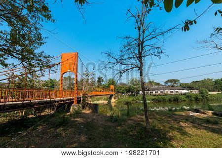 Wide angle picture of the Nam Song River with tropical vegetation orange bridge and a closed resort. Near to Tham Chang Cave in the city of Vang Vieng Laos.